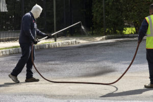 Nashville Asphalt Contractor wearing protective clothing spraying Asphalt Sealcoating in parking lot in a condo complex in Davidson County