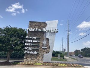 Image of a shopping center sign in West Nashville. The area is in need of asphalt patching